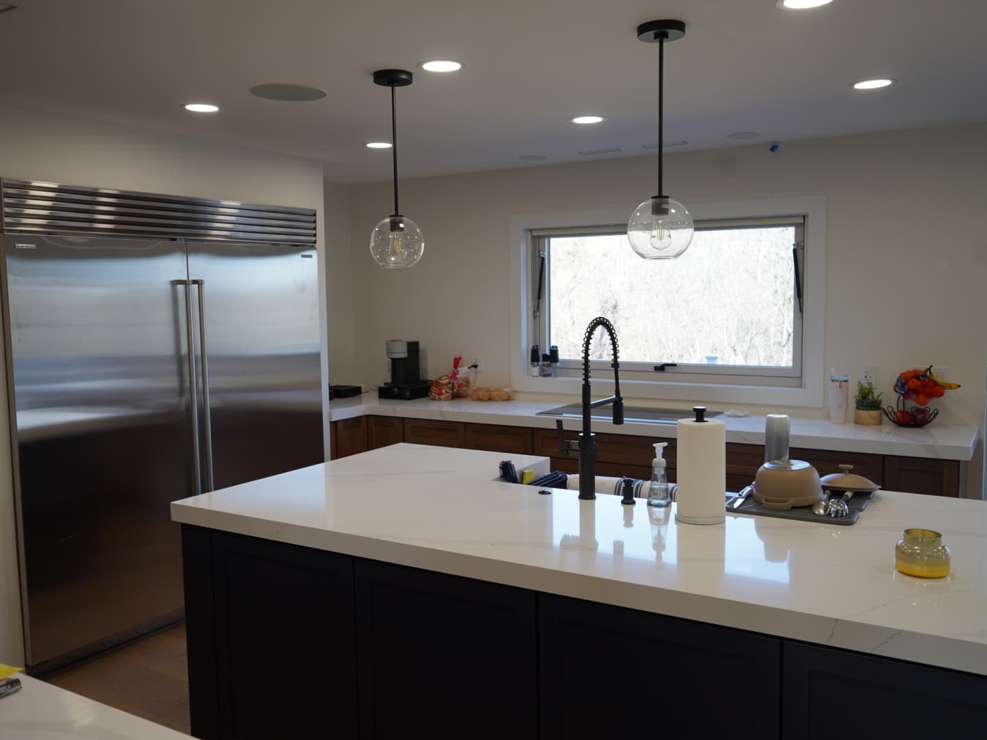 High-end kitchen remodel with island, premium appliances, wood perimeter cabinets, and updated lighting by RHI Pros.