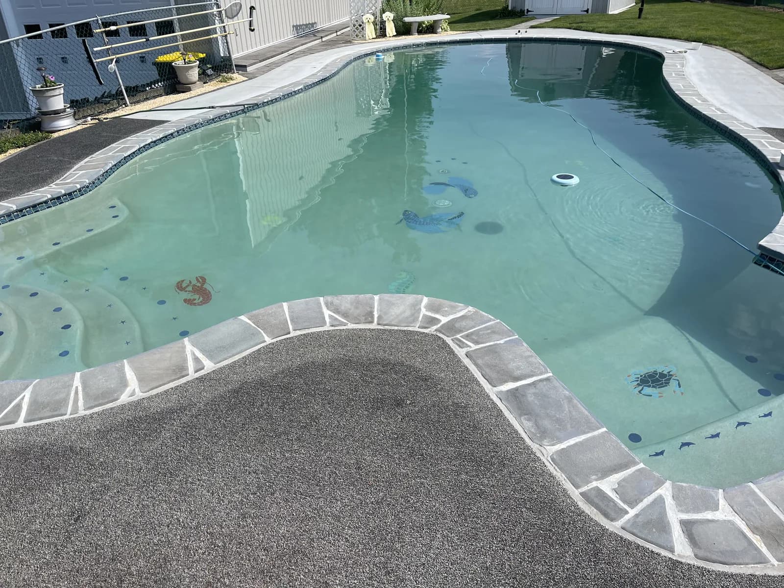 Matching pool shape with a gray textured surround and light stone-pattern border.