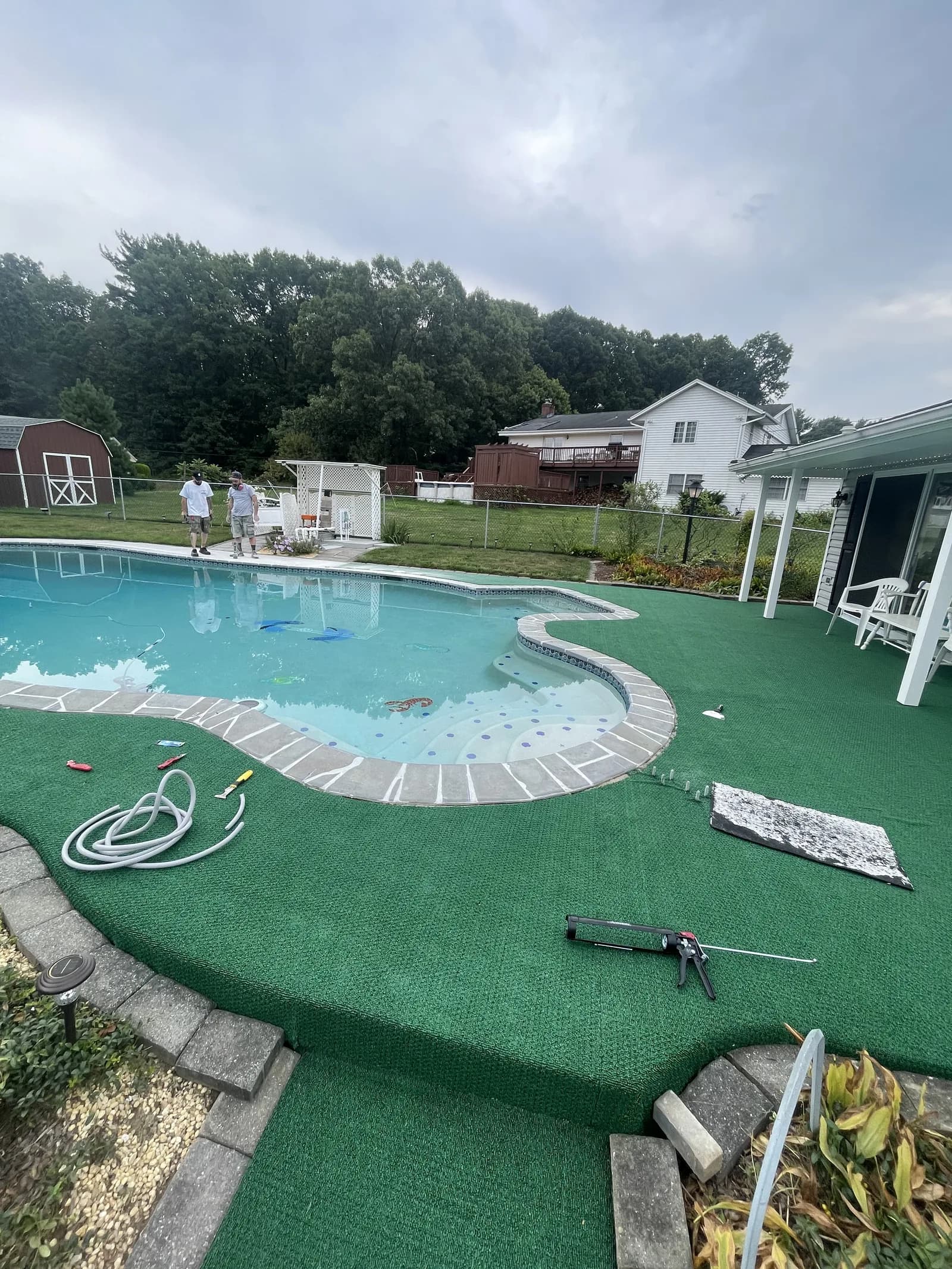 Supplied earlier-condition view of the curved pool with a green surrounding surface.